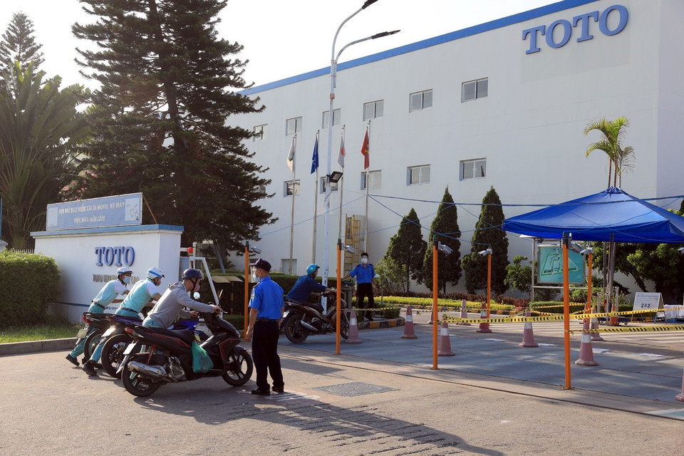 Lực lượng bảo vệ Công ty TOTO Việt Nam hướng dẫn công nhân đi theo làn đường quy định trước khi vào công ty. (Ảnh: Phan Tuấn Anh/TTXVN)