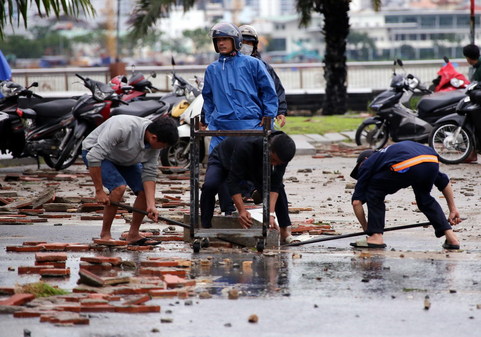 Di chuyển các tảng đá lớn bị sóng đánh bay ra đường giao thông do bão số 6 gây ra. (Ảnh: Trần Lê Lâm/TTXVN)