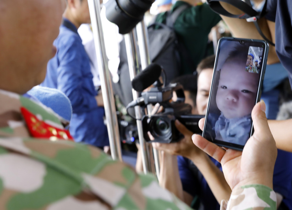 Cuộc điện thoại chào tạm biệt con nhỏ 4 tháng tuổi của một chiến sỹ công binh trước giờ lên đường làm nhiệm vụ. (Ảnh: An Đăng/TTXVN)