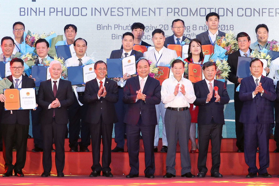 Thủ tướng Nguyễn Xuân Phúc, nguyên Chủ tịch nước Nguyễn Minh Triết và các doanh nghiệp nhận giấy chứng nhận đăng ký đầu tư, quyết định chủ trương đầu tư vào tỉnh Bình Phước. (Ảnh: Thống Nhất/TTXVN)