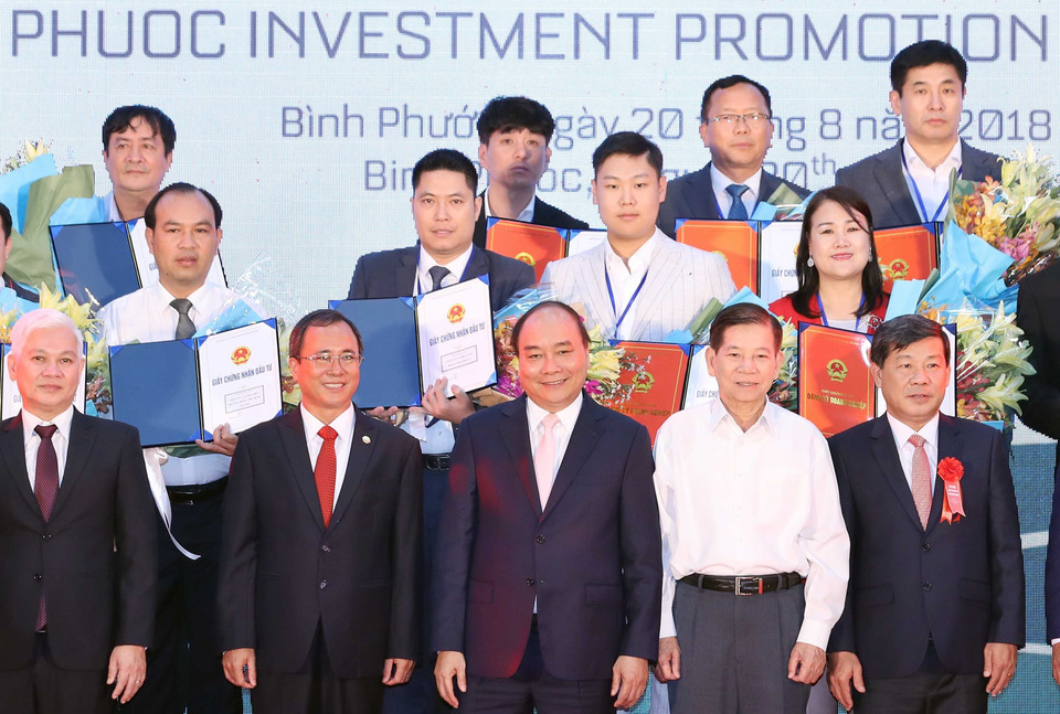 Thủ tướng Nguyễn Xuân Phúc chụp ảnh chung với các doanh nghiệp nhận giấy chứng nhận đăng ký đầu tư, quyết định chủ trương đầu tư vào tỉnh Bình Phước. (Ảnh: Thống Nhất/TTXVN)