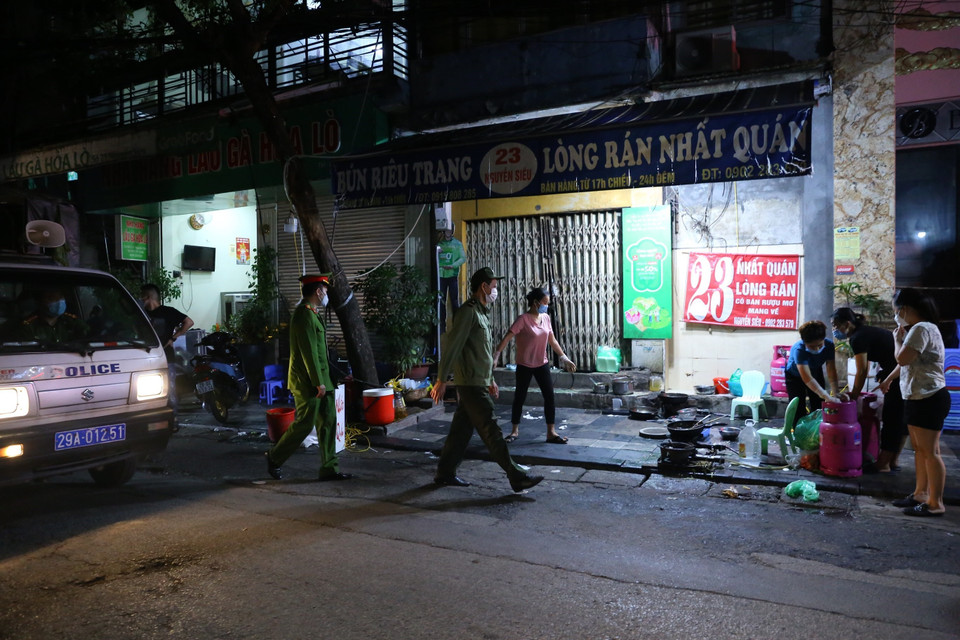 Lực lượng chức năng phường Hàng Bồ (quận Hoàn Kiếm) nhắc nhở các hộ kinh doanh ăn uống trên địa bàn đóng cửa đúng 21 giờ. (Ảnh: Hoàng Hiếu/TTXVN)