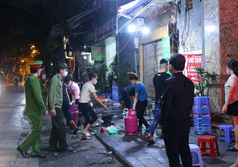 Lực lượng chức năng phường Hàng Bồ (quận Hoàn Kiếm) nhắc nhở các hộ kinh doanh ăn uống đóng cửa đúng 21 giờ. (Ảnh: Hoàng Hiếu/TTXVN)