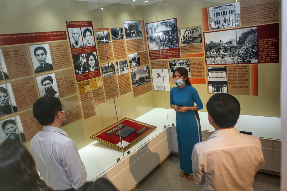 Hướng dẫn viên giới thiệu ảnh, các hiện vật tại gian trưng bày. (Ảnh: Tuấn Đức/TTXVN)