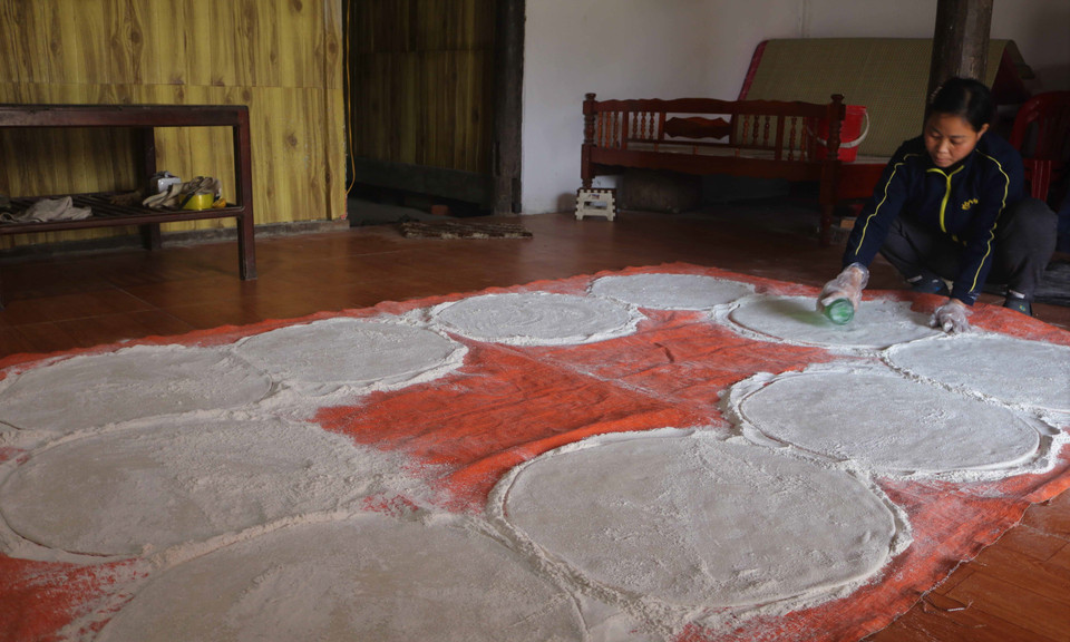 Từ những bàn tay khéo léo của các bà, các chị, Pẻng Khua (bánh cười) được cán ra mỏng có phủ lớp bột sắn mịn. (Ảnh: Chu Hiệu/TTXVN)