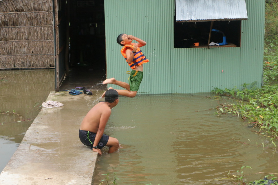 Những đứa trẻ ở xã Vĩnh Trị (Vĩnh Hưng, Long An) chơi đùa trong nước lũ ngay trước sân nhà. (Ảnh: Trường Giang/TTXVN)