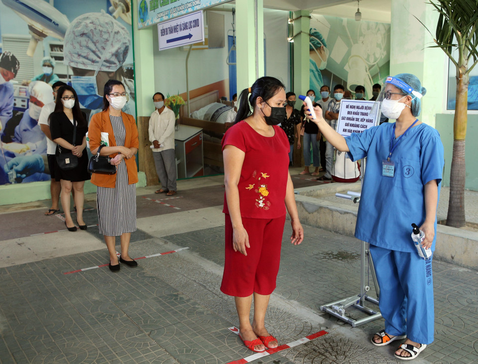 Người dân đến khám bệnh thực hiện giãn cách, được đo nhiệt độ, khai báo y tế để phân luồng bệnh nhân trước khi vào khu vực khám tại Bệnh viện Đà Nẵng. (Ảnh: Trần Lê Lâm/TTXVN)