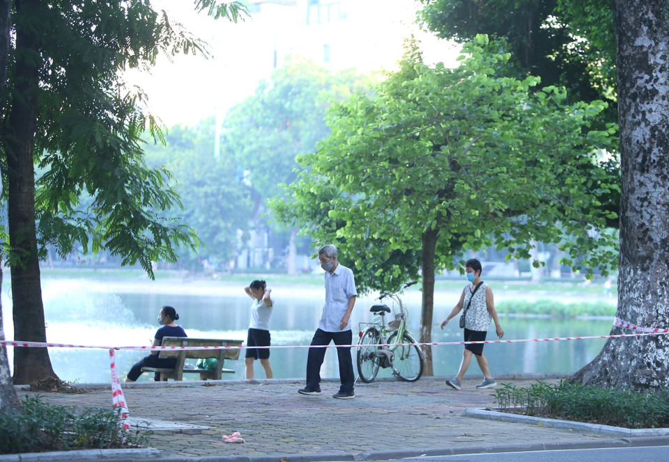 Nhiều người dân vẫn tập thể dục tại khu vực hồ Thiền Quang dù đã được lực lượng chức năng căng dây, cắm biển cấm (ảnh chụp lúc 5h50 ngày 13/7). (Ảnh: Hoàng Hiếu/TTXVN)