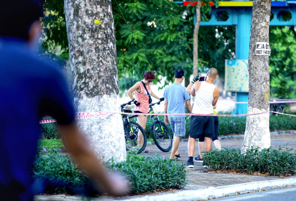 Một số người dân vẫn không đeo khẩu trang, tập thể dục khu vực ven hồ ven hồ Thiền Quang (dù lực lượng Công an phường Nguyễn Du đã căng dây, để biển báo yêu cầu không vi phạm. Ảnh chụp 5h50 ngày 13/7/2021). (Ảnh: Hoàng Hiếu/TTXVN)