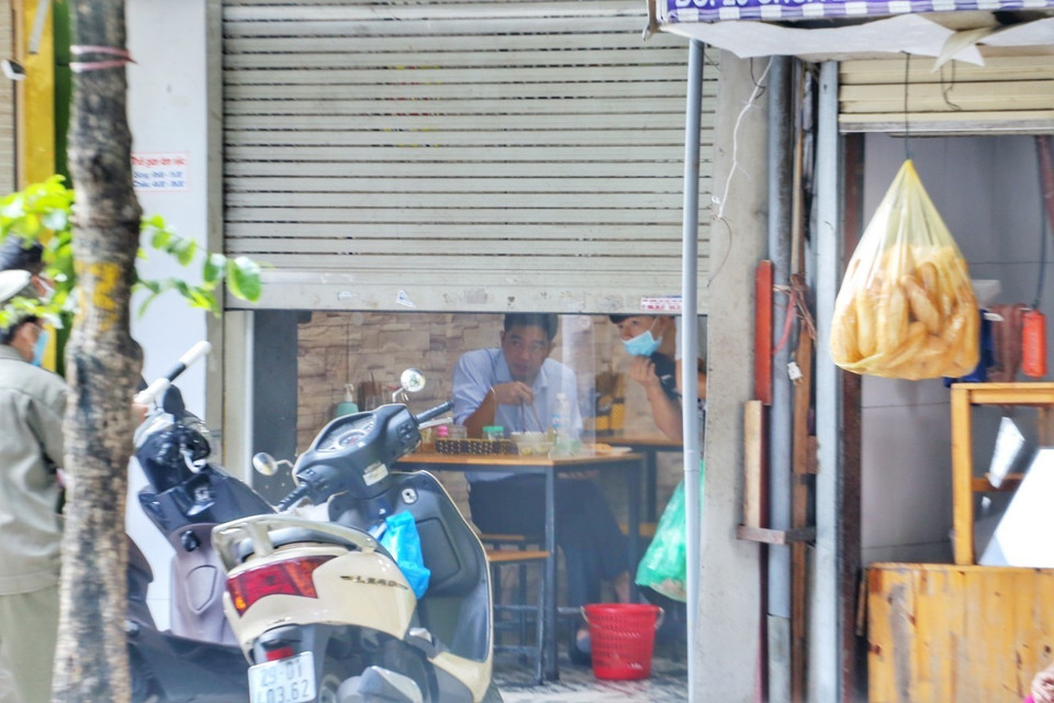 Một quán ăn cố tình mở cửa cho khách ăn sáng trong nhà bị lực lượng chức năng nhắc nhở. (Ảnh: Tuấn Đức/TTXVN)