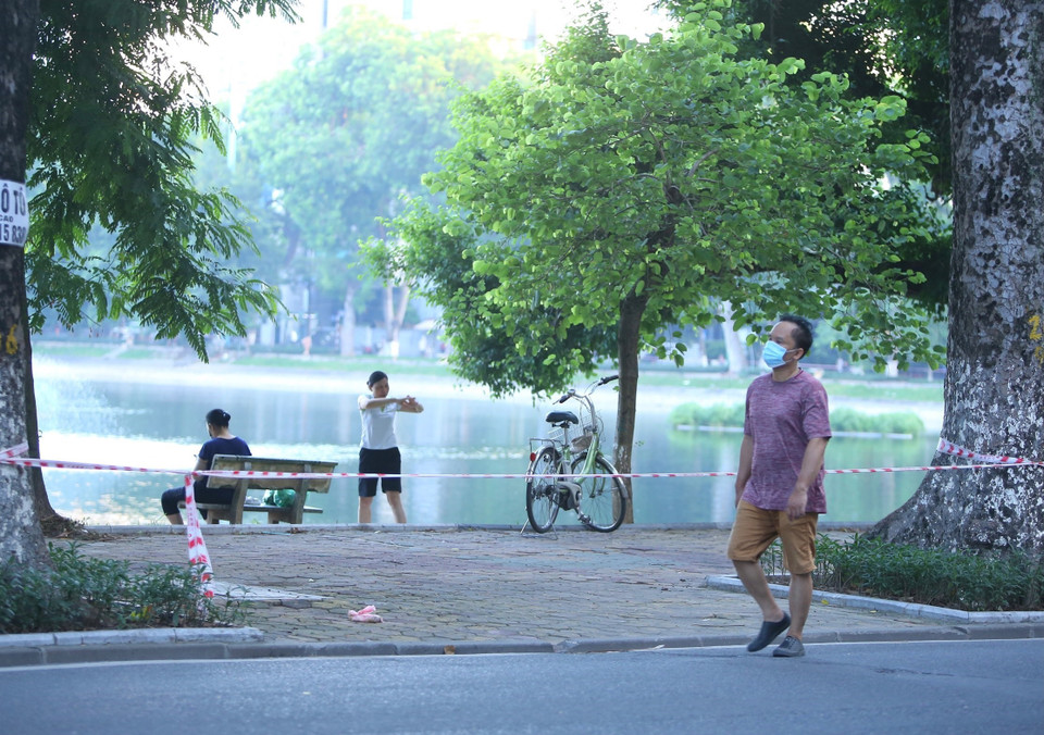 Nhiều người dân vẫn tập thể dục tại khu vực hồ Thiền Quang dù đã được lực lượng chức năng căng dây, cắm biển cấm (ảnh chụp lúc 5h50 ngày 13/7). (Ảnh: Hoàng Hiếu/TTXVN)