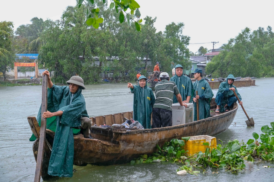 Lực lượng dân quân, bảo vệ dân phố dùng thuyền hỗ trợ các hộ dân di dời tài sản từ khu vực nhà bị sạt không thể tiếp cận bằng đường bộ. (Ảnh: Thanh Liêm/TTXVN)