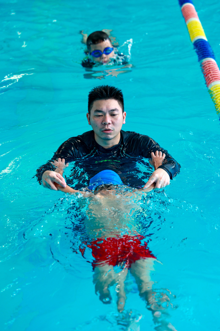 Hướng dẫn viên đang hỗ trợ động tác bơi cho một em nhỏ. (Ảnh: Minh Hiếu/Vietnam+)