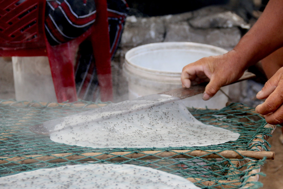 Bánh tráng được làm hoàn toàn từ bột mì (sắn) và vừng, dùng bếp củi để tráng tạo nên những chiếc bánh thơm ngon đặc trưng vùng biển. (Ảnh: Nguyễn Thanh/TTXVN)