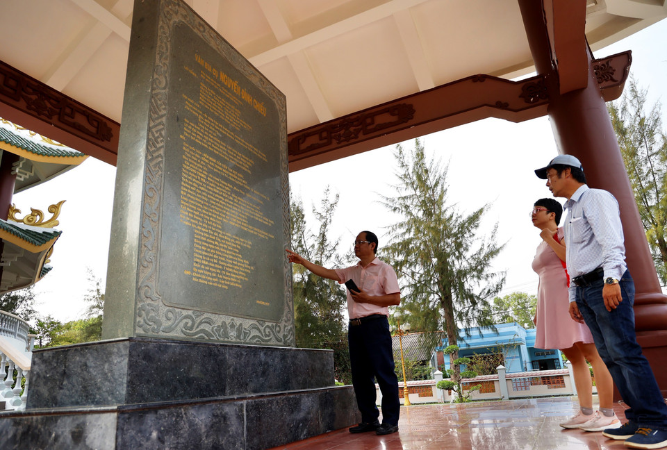 Du khách nghe giới thiệu về bia đá khắc bài văn ca ngợi công đức của Nguyễn Đình Chiểu. (Ảnh: Hồng Đạt/TTXVN)