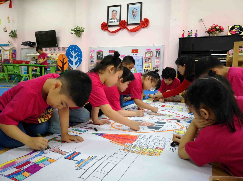 Cô và trò lớp học mang tên Kim Nhật Thành cùng hoàn thành bức tranh về chủ đề tình hữu nghị Việt Nam-Triều Tiên. (Ảnh: Thanh Tùng/TTXVN)