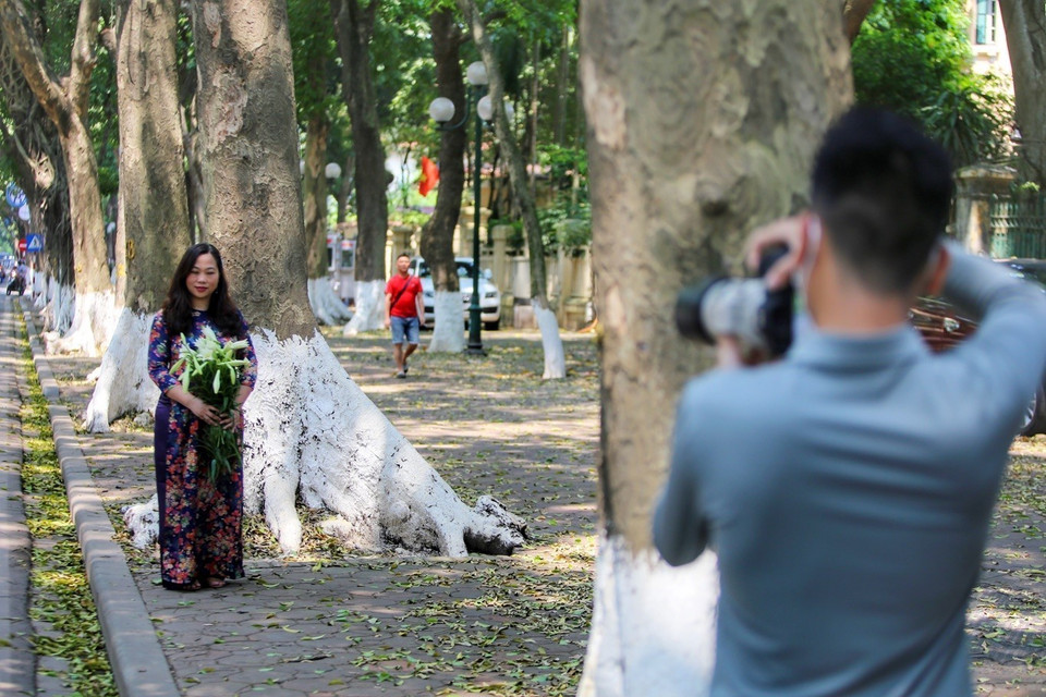 Người dân Thủ đô chụp ảnh với hoa loa kèn. (Ảnh: Tuấn Đức/TTXVN)