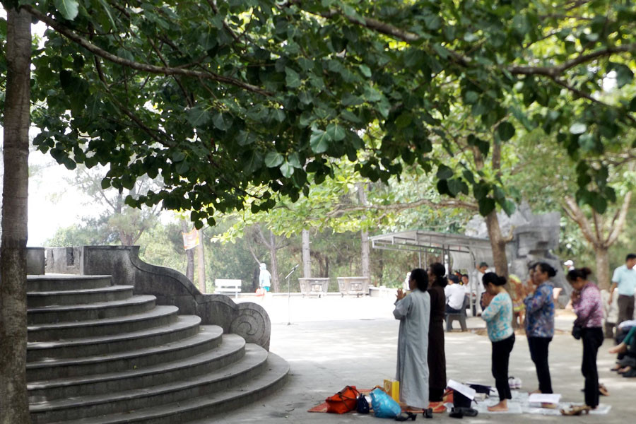 Dưới gốc bồ đề, một nhóm người hành lễ với hương hồn các liệt sỹ. (Ảnh: T.H/Vietnam+)