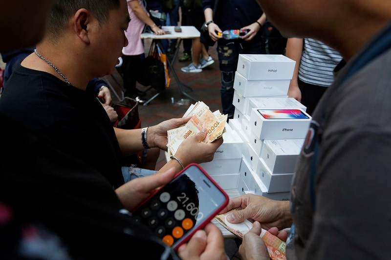 Một người đàn ông thu mua lại iPhone X ngay trước cửa hàng của Apple. (Nguồn: Reuters)