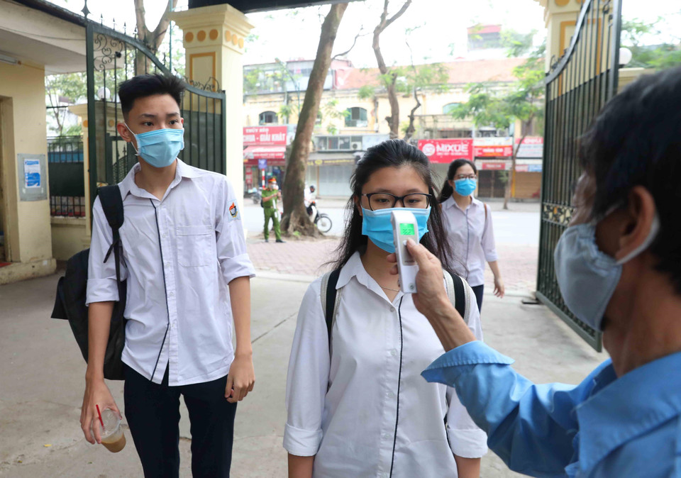 Học sinh trường THPT Việt Đức, quận Hoàn Kiếm được đo kiểm tra thân nhiệt trước khi vào trường theo đúng quy định. (Ảnh: Thành Đạt/TTXVN)