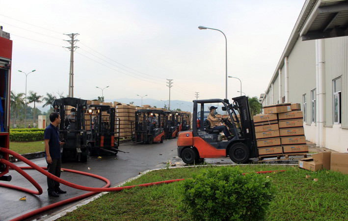 Công nhân nhà máy di chuyển hàng hóa trong kho, xưởng đến nơi an toàn. (Ảnh: Văn Đức/TTXVN)