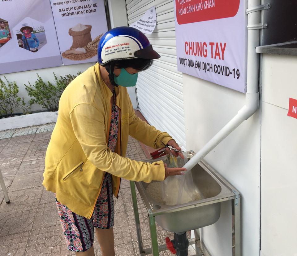 Người nghèo Thành phố Hồ Chí Minh xếp hàng nhận gạo miễn phí từ cây ATM gạo. (Ảnh: TTXVN)