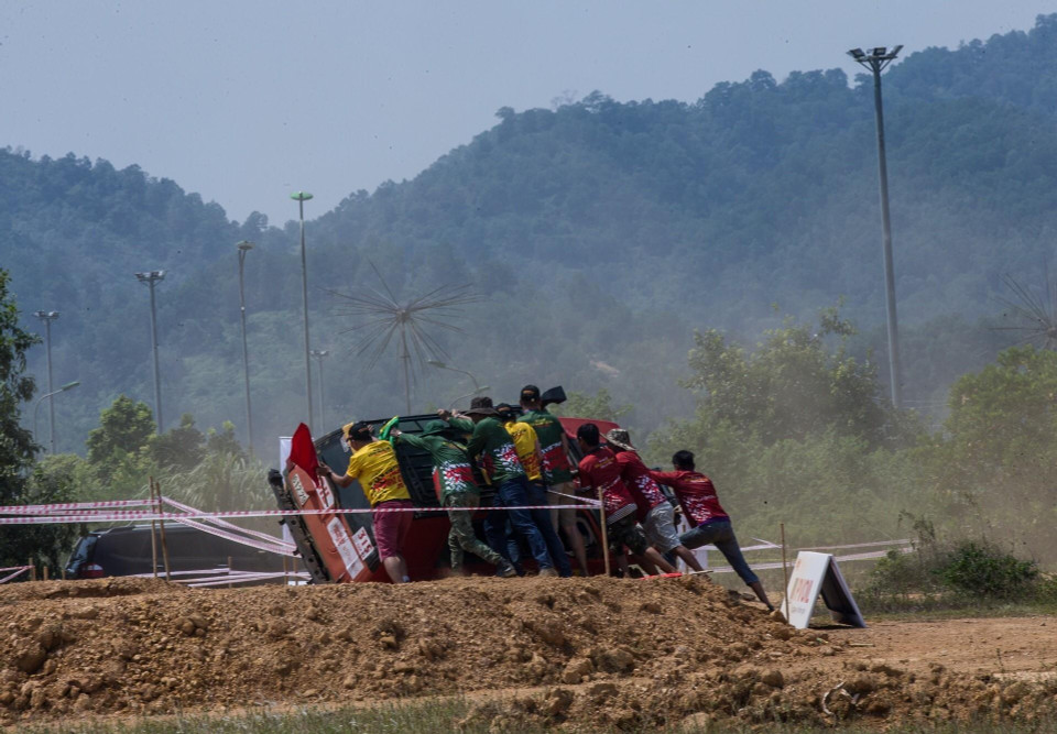 Một đội thi bị nghiêng xe khi vào cua địa hình xấu ở tốc độ cao, được nhân viên cứu hộ giúp lật lại xe để tiếp tục cuộc đua. (Ảnh: Trọng Đạt/TTXVN)