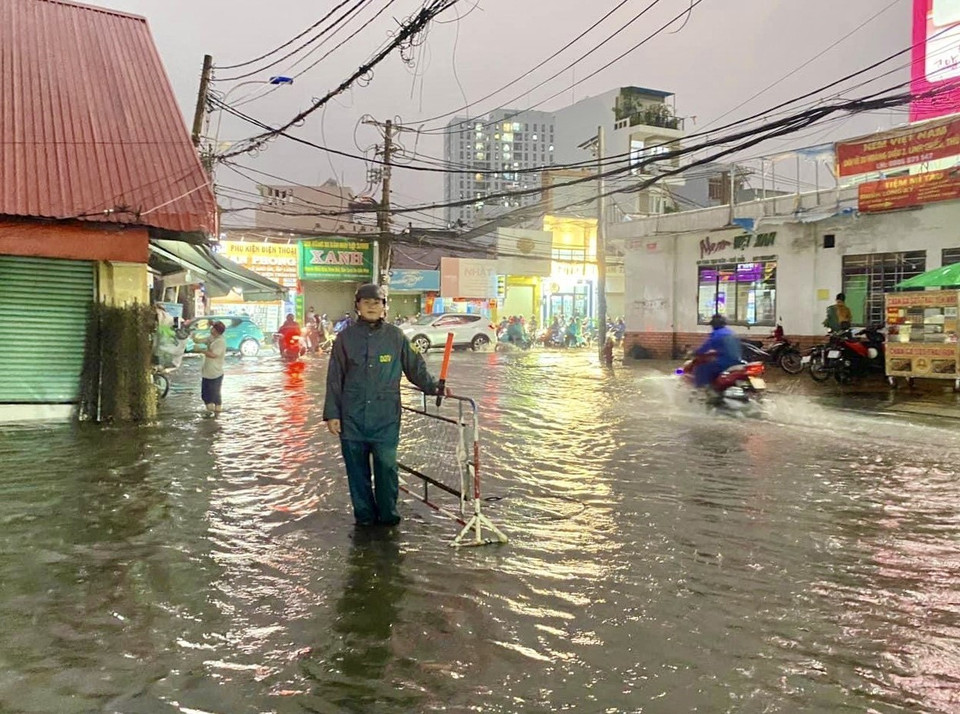 Lực lượng dân phòng dựng rào chắn xung quanh khu vực nước ngập tại chợ Thủ Đức (thành phố Thủ Đức, Thành phố Hồ Chí Minh) để cảnh báo an toàn và hướng dẫn người đi đường. (Ảnh: Hồng Giang/TTXVN)