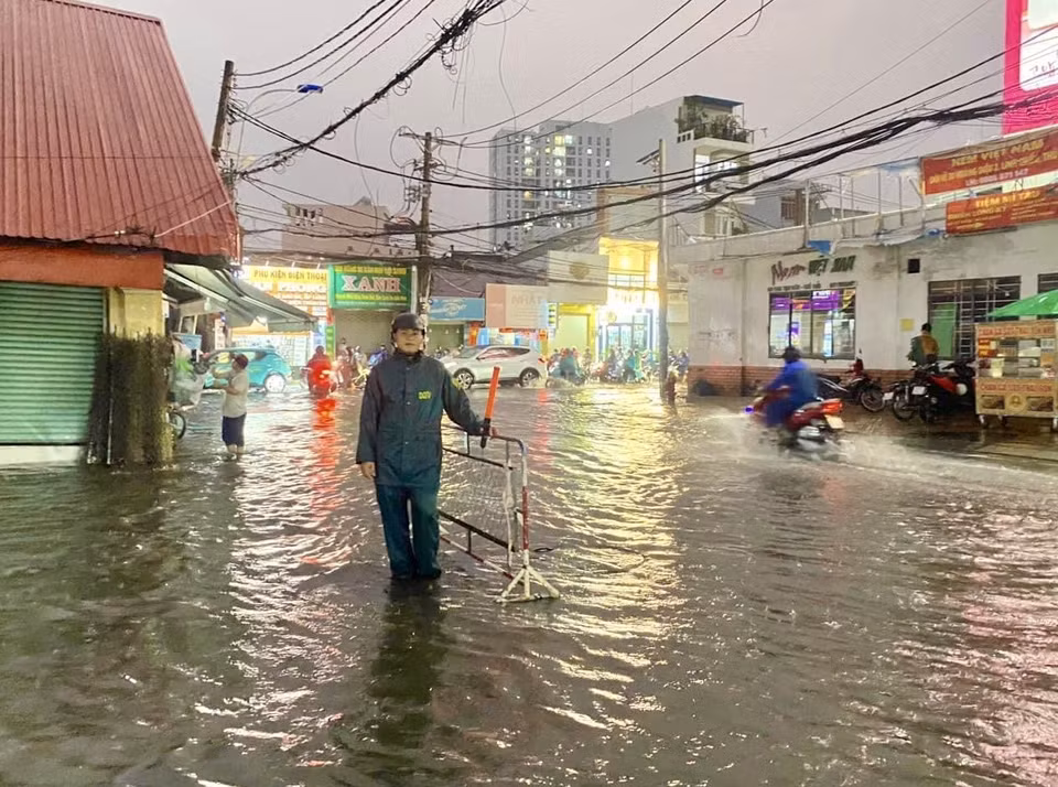Lực lượng dân phòng dựng rào chắn xung quanh khu vực nước ngập tại chợ Thủ Đức (thành phố Thủ Đức, Thành phố Hồ Chí Minh) để cảnh báo an toàn và hướng dẫn người đi đường. (Ảnh: Hồng Giang/TTXVN)