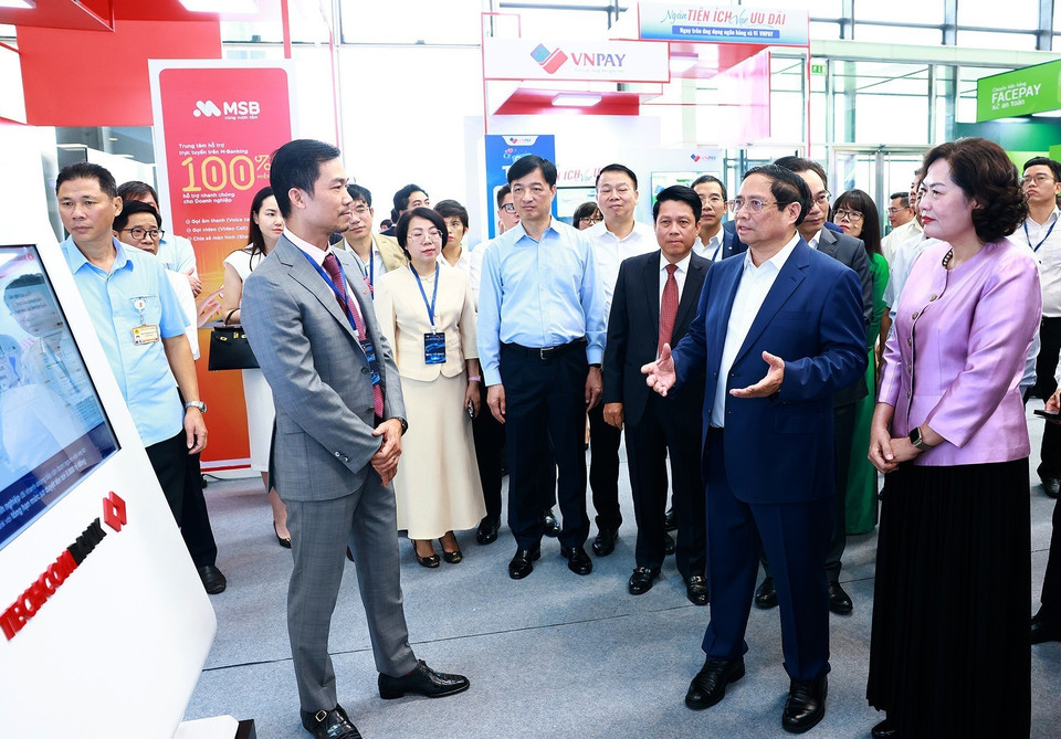 Thủ tướng Phạm Minh Chính tham quan trưng bày về ứng dụng chuyển đổi số trong lĩnh vực ngân hàng. (Ảnh: Dương Giang/TTXVN)