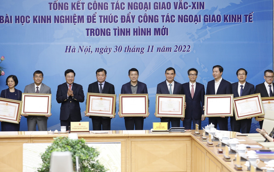 Phó Thủ tướng thường trực Phạm Bình Minh và Phó Thủ tướng Vũ Đức Đam trao Bằng khen của Thủ tướng cho các cá nhân có thành tích xuất sắc trong triển khai công tác ngoại giao vaccine. (Ảnh: Dương Giang/TTXVN)