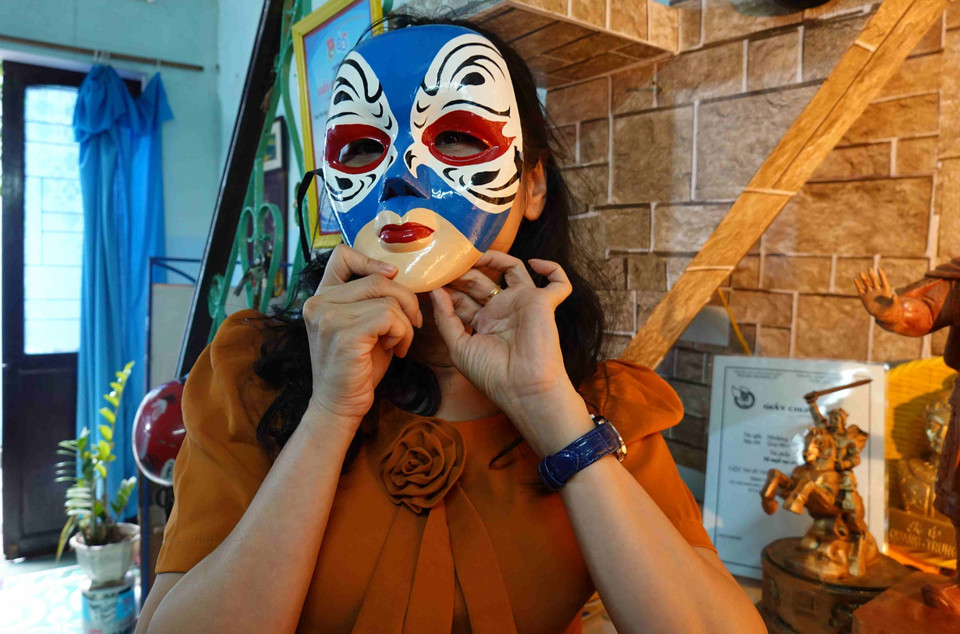 Du khách thích thú với những chiếc mặt nạ chân dung nghệ thuật hát bội của ông Vân. (Ảnh: Tường Quân/TTXVN)