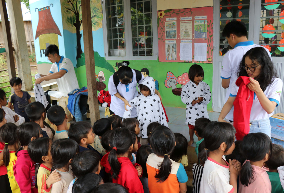 Các em học sinh nhóm thiện nguyện Fly to Sky mang áo ấm đến cho trẻ em làng Đê Kôn. (Ảnh: Hồng Điệp/TTXVN)