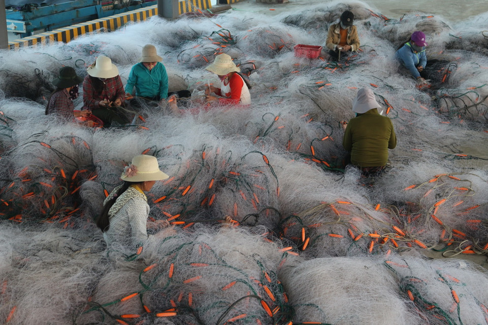 Phụ nữ nông thôn vùng ven biển tỉnh Nghệ An đan lưới phục vụ khai thác biển. (Ảnh: Nguyễn Oanh/TTXVN)