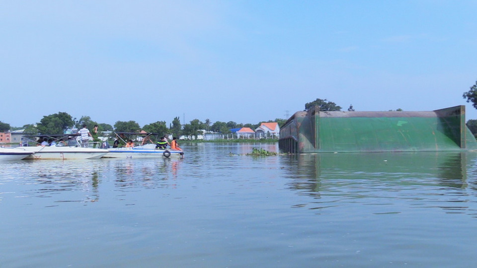 Lực lượng tìm kiếm quần thảo xung quanh chiếc sà lan bị lật úp đề tìm người mất tích dưới sông. (Ảnh: Nguyễn Văn Việt/TTXVN)