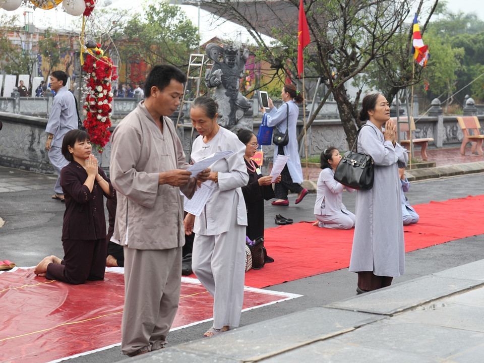 Người chồng lặng lẽ đọc kinh, niệm phật cầu cho linh hồn người đã khuất siêu thoát… (Ảnh: Doãn Đức/Vietnam+)