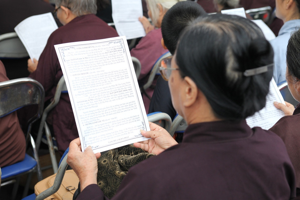 Một mẹ cũng có con tử vong vì tai nạn giao thông chậm rãi đọc bài kinh cầu. (Ảnh: Doãn Đức/Vietnam+)