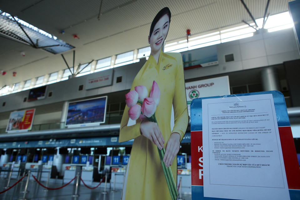Hãng hàng không Vietnam Airlines dán bảng thông báo hủy toàn bộ chuyến bay đi/đến Đà Nẵng trong ngày 28/7 tại Ga đi tại Cảng Hàng không quốc tế Đà Nẵng do dịch COVID-19. (Ảnh: Trần Lê Lâm/TTXVN)