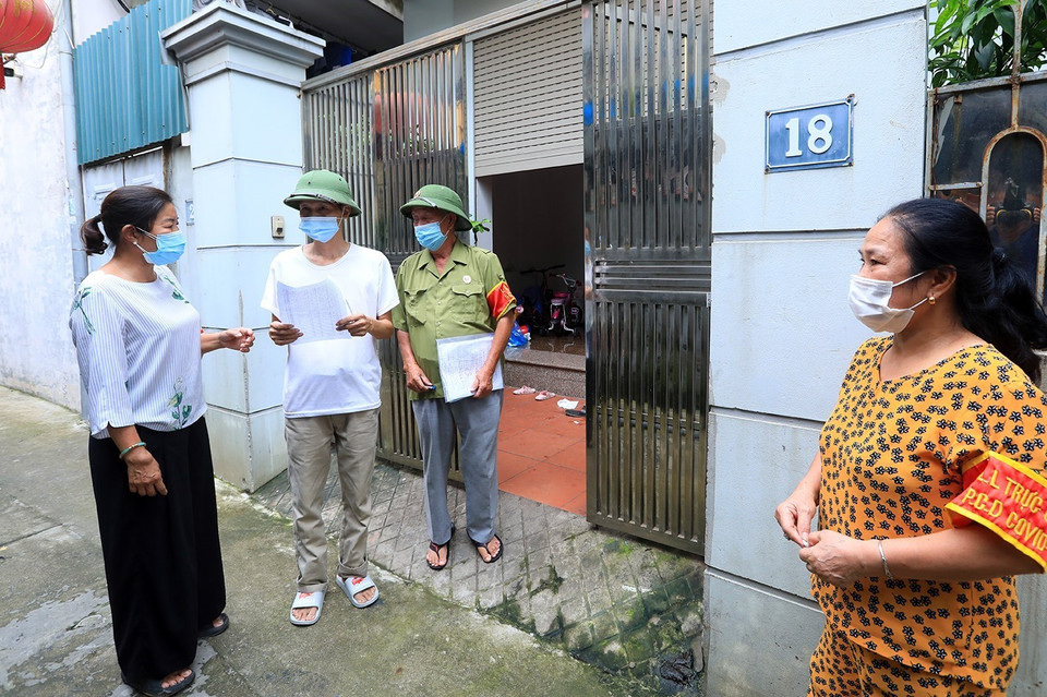 Thành viên Tổ phòng, chống COVID cộng đồng phối hợp đi từng ngõ, gõ từng nhà để tuyên truyền, nhắc nhở người dân đi lấy mẫu xét nghiệm COVID-19. (Ảnh: Tuấn Anh/TTXVN)