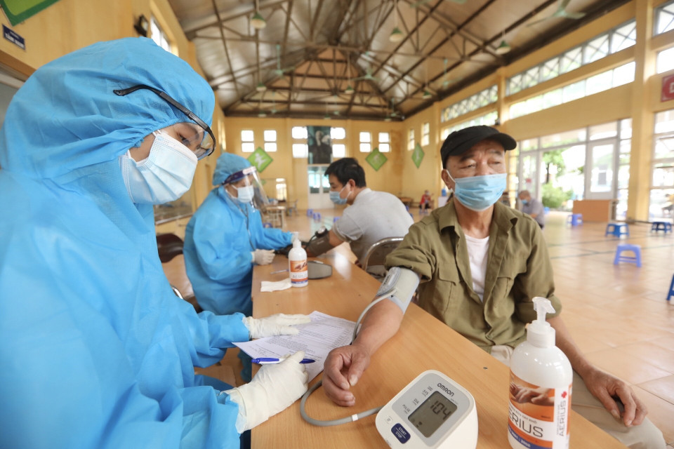 Người dân xã Tam Hiệp, huyện Thanh Trì được kiểm tra thân nhiệt, khai báo y tế, khám sàng lọc trước khi tiêm vaccine phòng COVID-19 tại điểm tiêm chủng. (Ảnh: Minh Quyết/TTXVN)