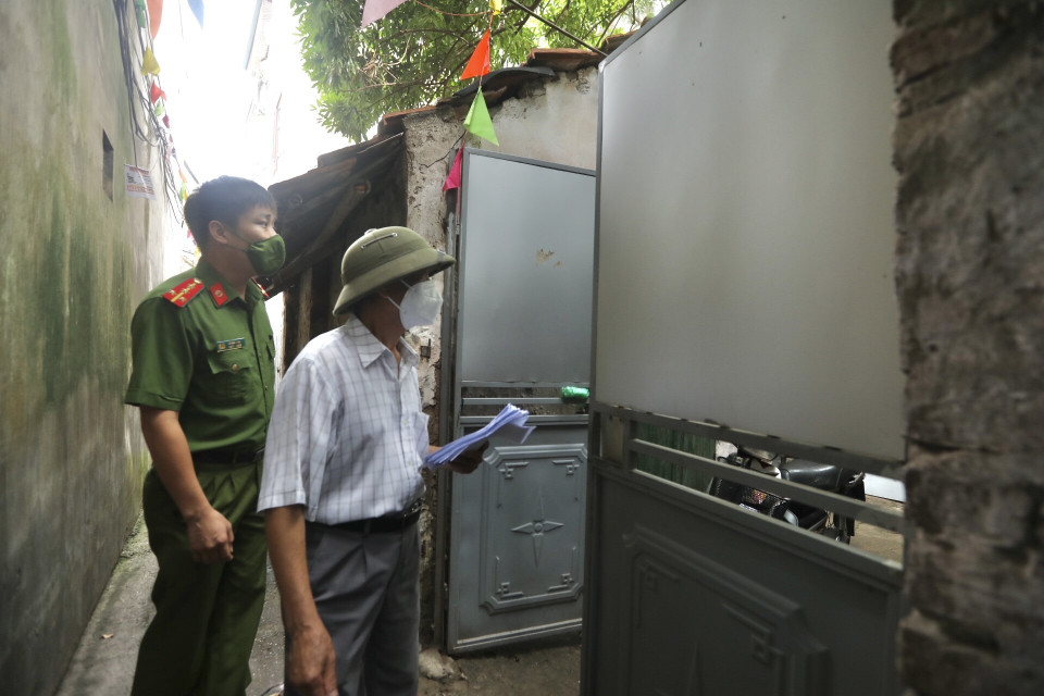 Thành viên Tổ phòng, chống COVID cộng đồng phối hợp đi từng ngõ, gõ từng nhà để tuyên truyền, nhắc nhở người dân đi lấy mẫu xét nghiệm COVID-19. (Ảnh: Minh Quyết/TTXVN)