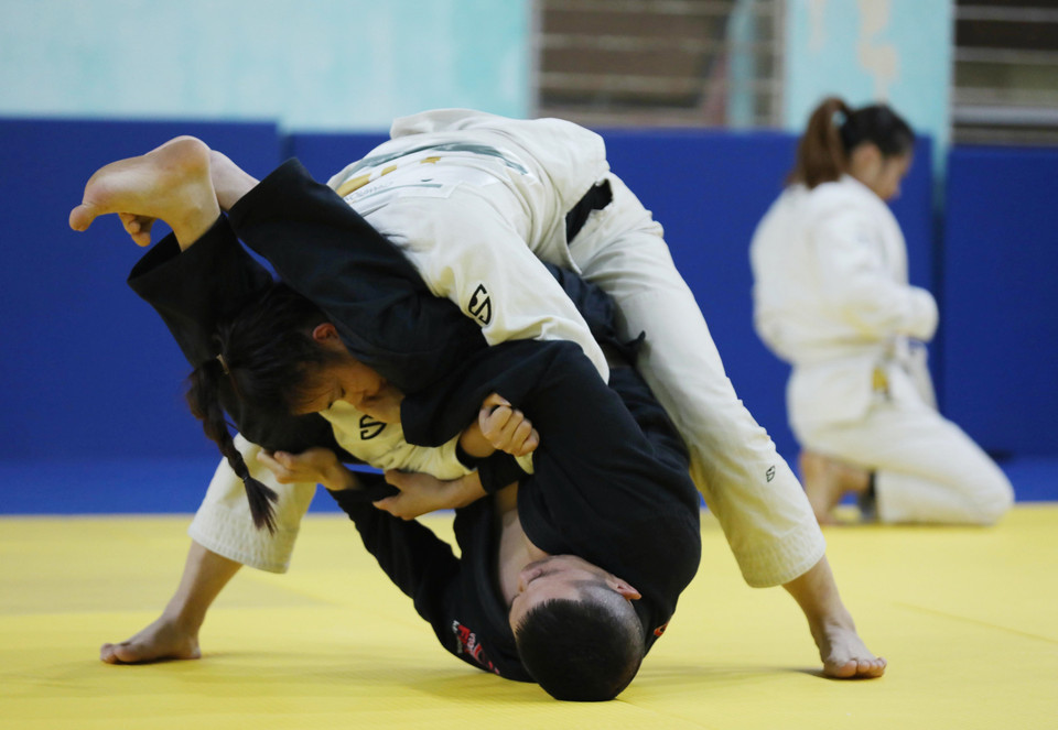 Vận động viên Hoàng Thị Nhật Quế tập luyện với huấn luyện viên Bùi Đình Tiến (áo đen). (Ảnh: Hoàng Hiếu/TTXVN)