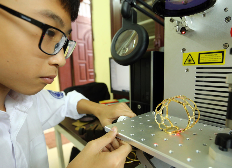 Bắn chữ lazer lên sản phẩm vòng vàng đeo tay. (Ảnh: Trần Việt/TTXVN)