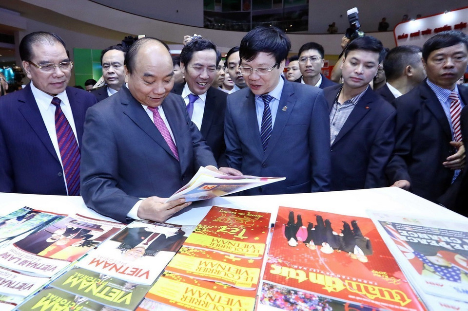 Thủ tướng Nguyễn Xuân Phúc, nguyên Tổng Bí thư Nông Đức Mạnh và các đại biểu xem các ấn phẩm tại gian trưng bày tại Hội báo toàn quốc năm 2019. (Ảnh: Thống Nhất/TTXVN)
