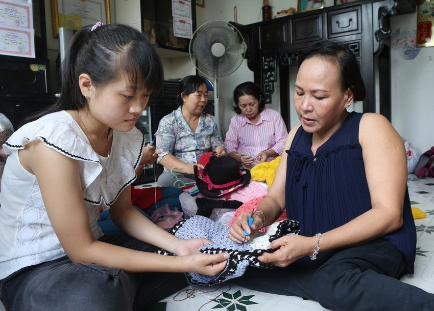 Chị Đinh Thị Tuyết Đào (bên phải) bị bại liệt từ nhỏ, hướng dẫn học viên Cơ sở đan len Phước Đào (174/12 Lê Văn Lương, phường Tân Hưng, quận 7, Thành phố Hồ Chí Minh) học cách móc len. (Ảnh: Phương Hoa/TTXVN)