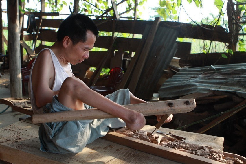 Anh Lê Hồng Sơn, chủ doanh nghiệp gỗ mỹ nghệ Mạnh Dũng (Hương Sơn, Hà Tĩnh) sử dụng đôi chân đặc biệt để sản xuất đồ mộc. Anh cũng mở nhiều lớp đào tạo nghề giúp cho người khuyết tật hòa nhập với cộng đồng. (Ảnh: Nguyễn Thủy/TTXVN)