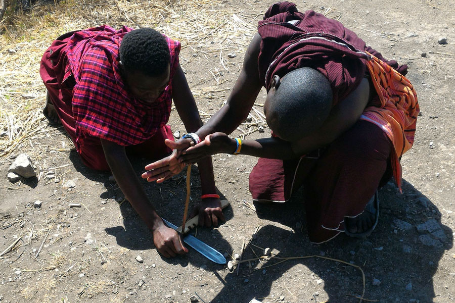 Người Maasai đánh lửa bằng cách để một con dao dưới đất, dùng hai thanh gỗ phía trên cọ sát vào nhau... (Ảnh: T.H/Vietnam+)