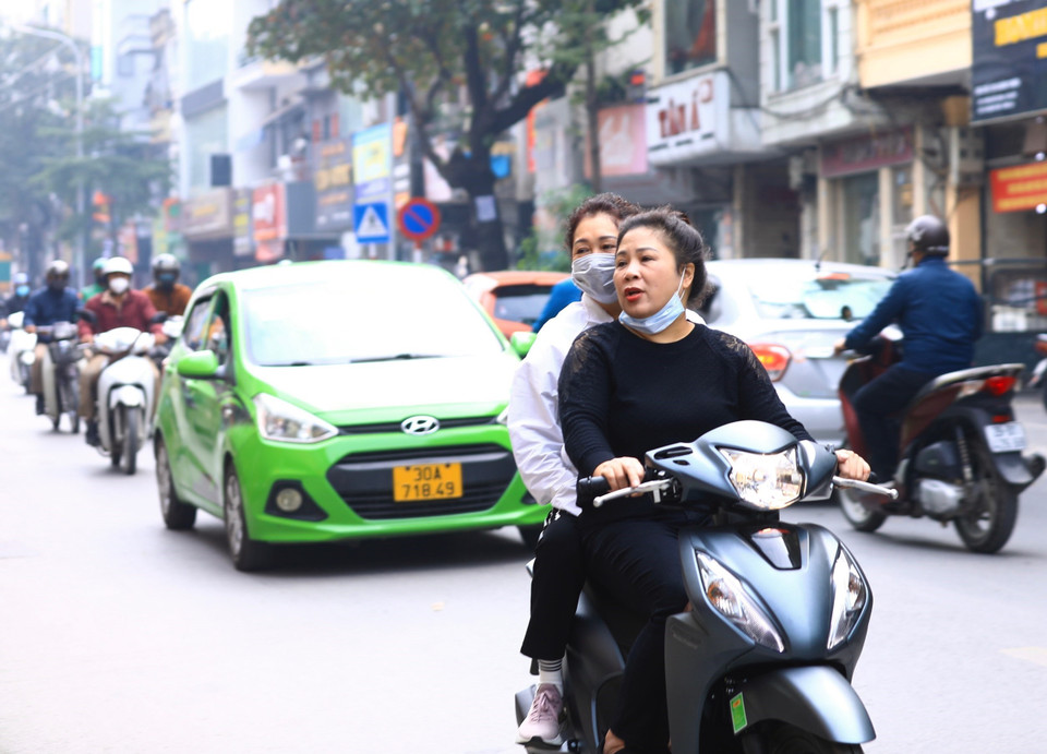  Người dân đeo khẩu trang không đúng cách khi tham gia giao thông trên phố Khâm Thiên (ảnh chụp sáng 10/12/2021). (Ảnh: Hoàng Hiếu/TTXVN)