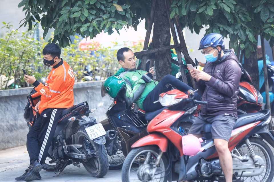 Một lái xe công nghệ không đeo khẩu trang trong lúc chờ khách. (Ảnh: Tuấn Anh/TTXVN)
