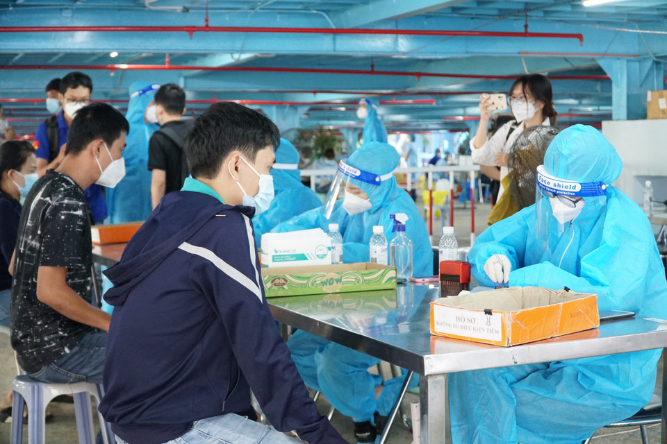 Nhân viên y tế tiếp nhận hồ sơ tiêm chủng trước khi người dân vào tiêm vaccine. (Ảnh: Thu Hương/TTXVN)